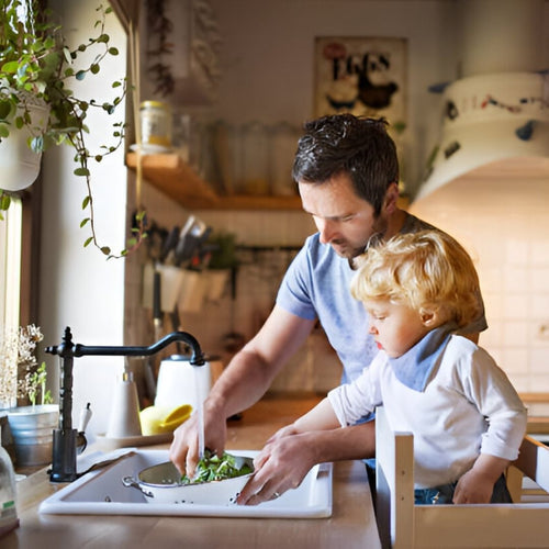 Man and baby son washing spinach in kitchen sink