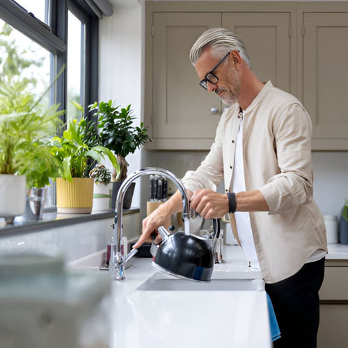 Man filling coffee kettle in kitchen sink