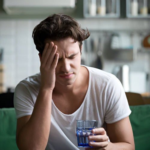 Man with headache looking stressed with glass of water