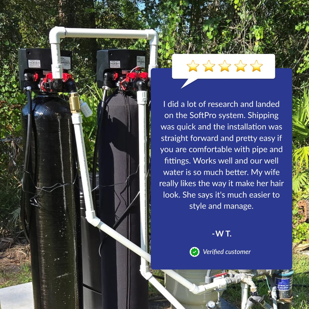 SoftPro Elite HE water softener system with two black tanks and white piping, set outdoors with a customer review.