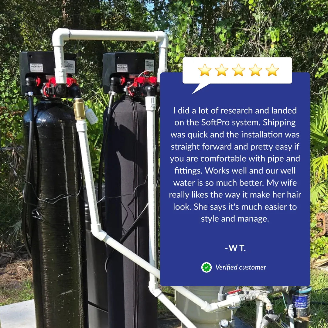 SoftPro Elite HE water softener system with two black tanks and white piping, set outdoors with a customer review.